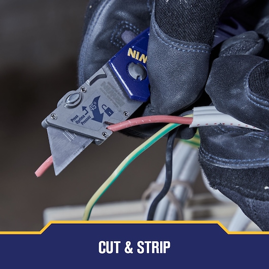 Photo of IRWIN utility knife SKU 2089100 cutting electrical wire, shown held by gloved hands.