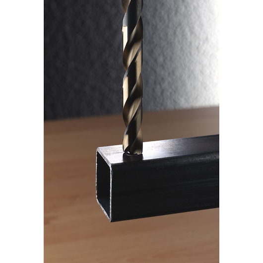 IRWIN 10502232 drill bit drilling into metal square tube, close-up side angle.