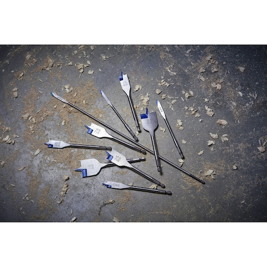 IRWIN 10502830 flat drill bits set with blue tips scattered on a workshop floor with wood shavings.