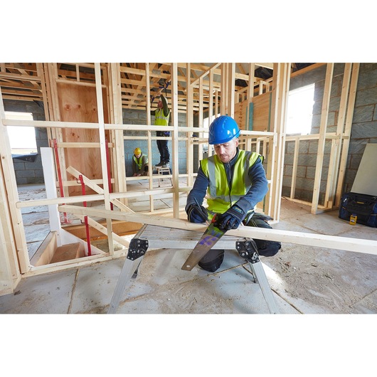 IRWIN 10505212 handsaw used by worker sawing wood, construction site, high-vis vest and blue helmet visible.