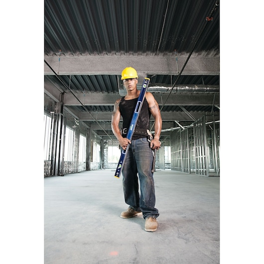 IRWIN 1794067 blue level tool held by worker in construction site, worker wearing yellow hard hat.