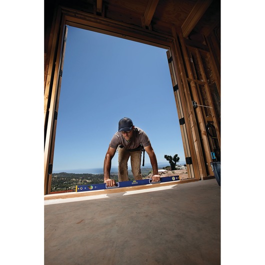 IRWIN 1794067 blue level tool used by worker at construction site in open doorway.