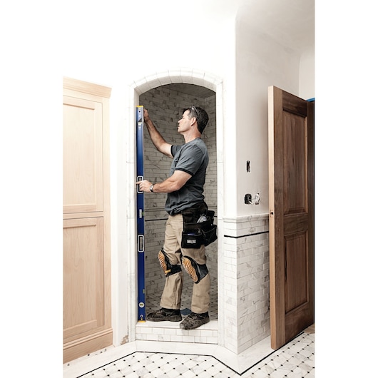 Photo of a person using an IRWIN 1794069 blue spirit level in a tiled doorway during construction work.