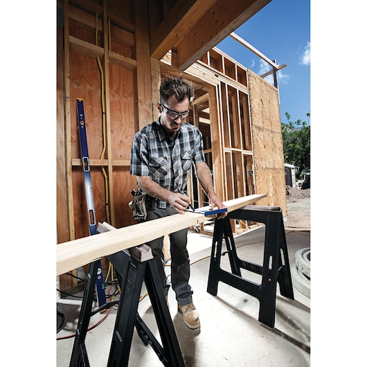 IRWIN 1794463 sawhorses supporting wood beam at construction site, worker marking measurement.