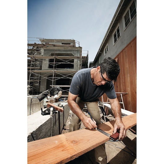 IRWIN carpenter marking wood plank with square ruler outdoors at construction site, SKU 1794472.