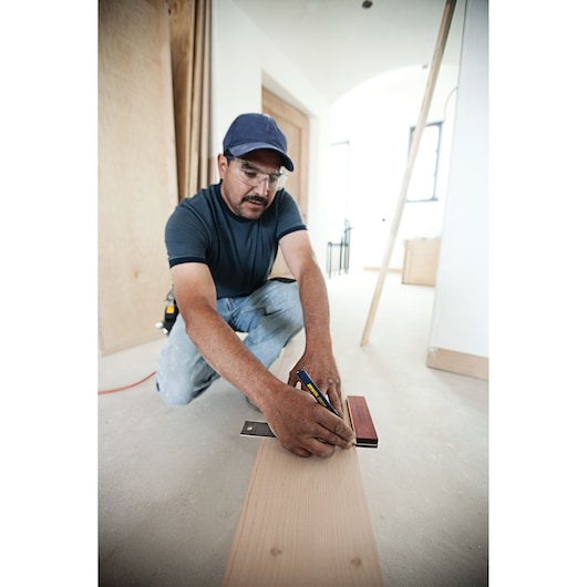 Photo of person using IRWIN 1794472 square to mark a wooden board in a construction setting.