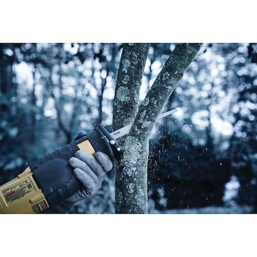 IRWIN 2018873 reciprocating saw blade cutting a tree branch outdoors, close-up with gloves visible.