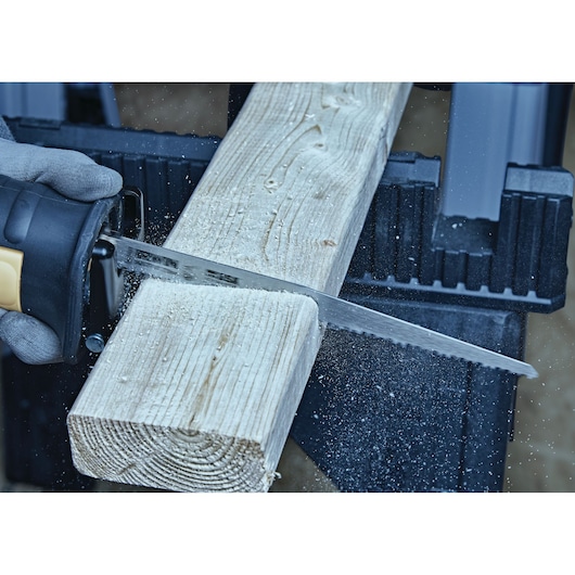 IRWIN 2018873 reciprocating saw blade cutting wood plank, close-up action shot with sawdust flying.