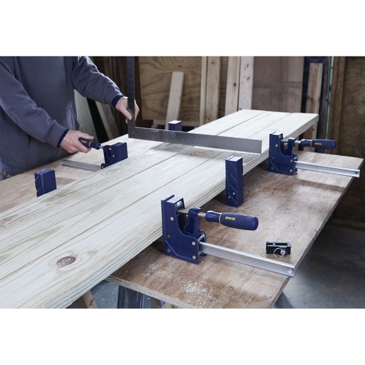 IRWIN 2026500 woodworking clamps securing boards on workbench, blue handle, workshop setting.