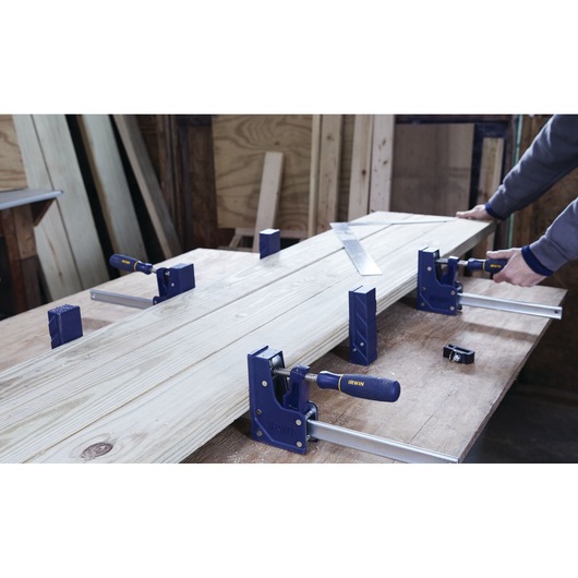 IRWIN 2026500 woodworking clamps holding boards on workbench in workshop, person adjusting clamp.