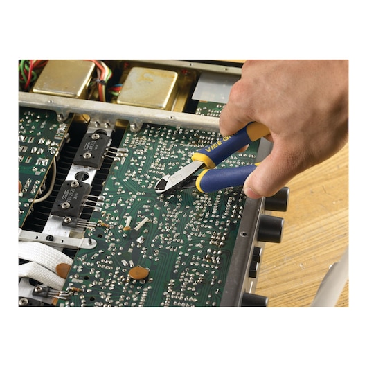 A hand is using IRWIN VISE-GRIP wire cutters to trim components on an electronic circuit board.