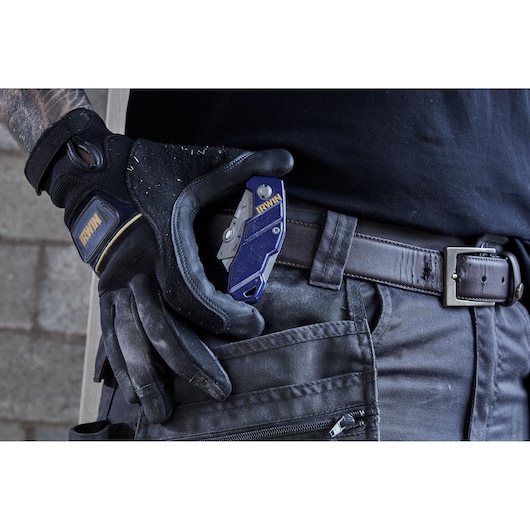Photo of IRWIN 2089100 utility knife held by gloved hand, clipped to dark pants pocket.