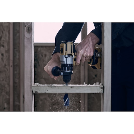 Photo of IRWIN 3041009 drill bit in use, drilling through wood frame in construction setting.