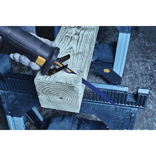 IRWIN 372156 reciprocating saw blade cutting a thick wood beam on a workbench, close-up side angle.