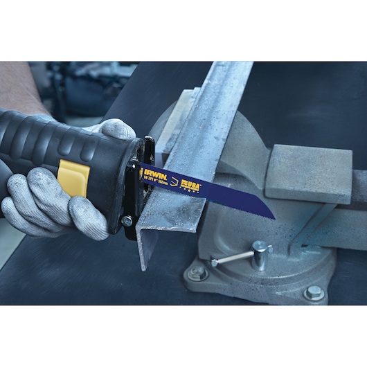 Photo of IRWIN 372618 reciprocating saw blade cutting metal angle iron in a vise, blue blade with yellow branding.