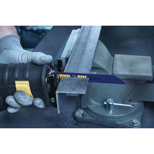 IRWIN 372618 reciprocating saw blade cutting metal angle iron in workshop, close-up with glove and vise.