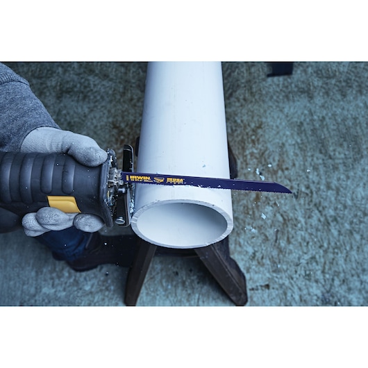 Photo of IRWIN 372810 reciprocating saw blade cutting white PVC pipe, close-up view with gloved hand.