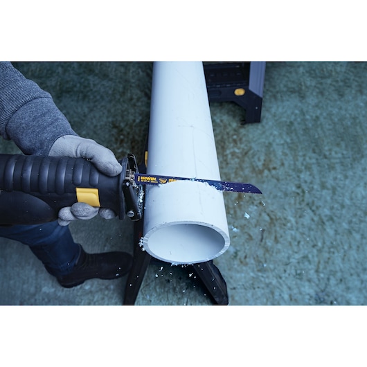 IRWIN 372810 reciprocating saw blade cutting large white PVC pipe held on a stand.