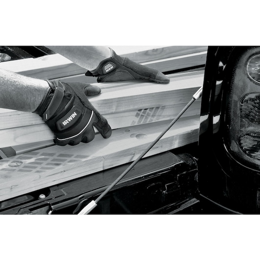 Photo of hands wearing IRWIN gloves 432005 loading wooden planks into a truck bed.