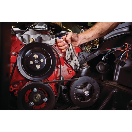 IRWIN IRHT82573 locking pliers used to grip a bolt on a red engine, close-up in automotive repair setting.