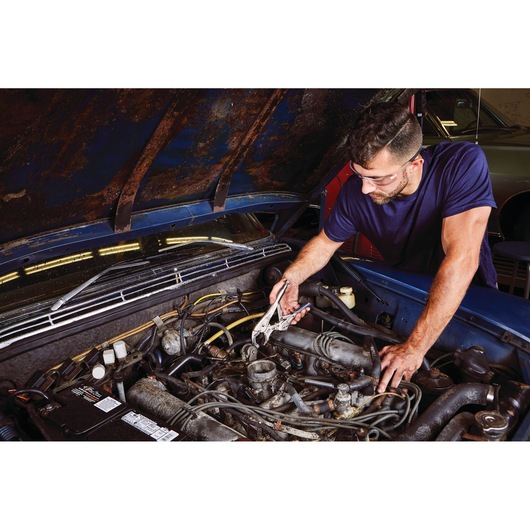 IRWIN IRHT82573 locking pliers clamping a part under the hood during car engine repair.