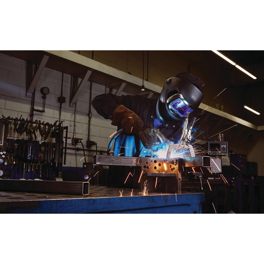 IRWIN IRHT82584 welding clamp in use during metal welding, sparks flying, in workshop setting.