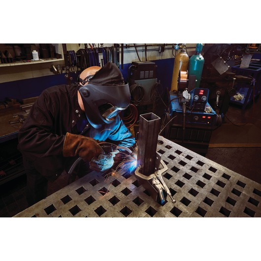 IRWIN IRHT82586 welding clamp secures metal tube on workshop table during welding process.