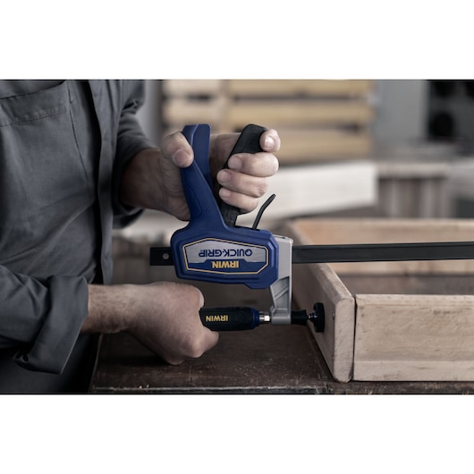 woodworker handling the clamp pressing boards on a table