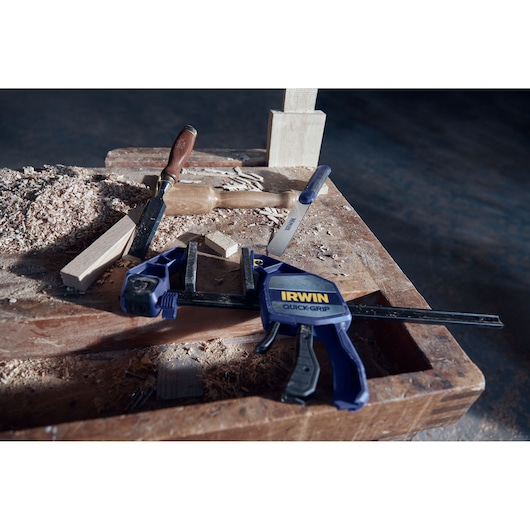 IRWIN 2011491 quick-grip clamp on workbench with wood and chisel, workshop setting.