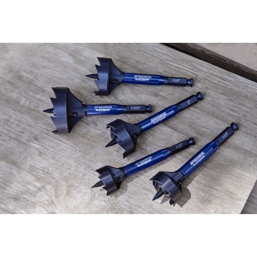 Five IRWIN Speedbor blue and black wood drill bits with screw tips are displayed on a wooden surface. The bits are designed for fast, clean hole drilling in wood.