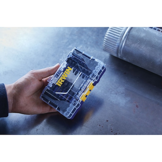 Photo of IRWIN IWAF1326 drill bit set in a transparent plastic case with yellow latch held in hand.