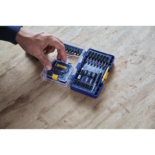 Photo of IRWIN drill bit set IWAF1326 in blue case on a wooden surface, hand opening the lid.