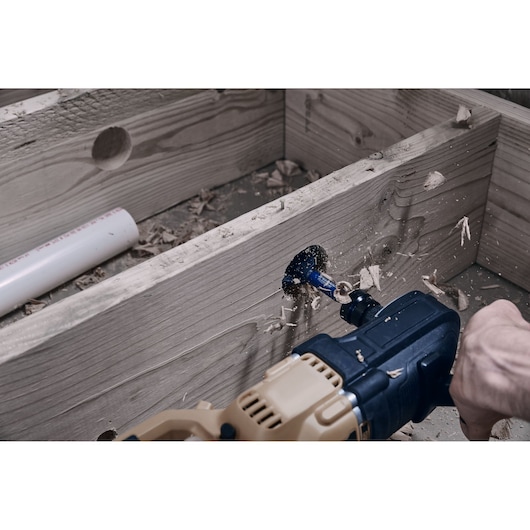 Photo of IRWIN IWAX2008 hole saw drilling through wooden board with power drill.