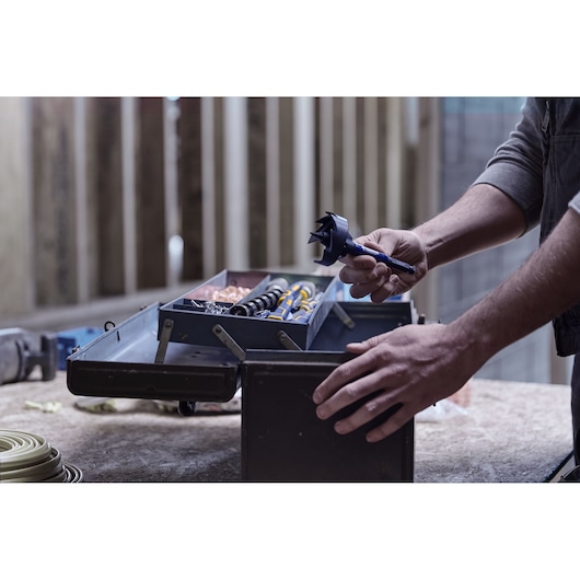 IRWIN drill bit and tool set IWAX2008 in open metal toolbox on workbench, hand holding large drill bit.