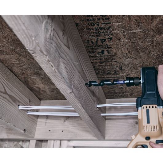 IRWIN IWAX3017 auger drill bit drilling through wood beam in construction, close-up side angle.
