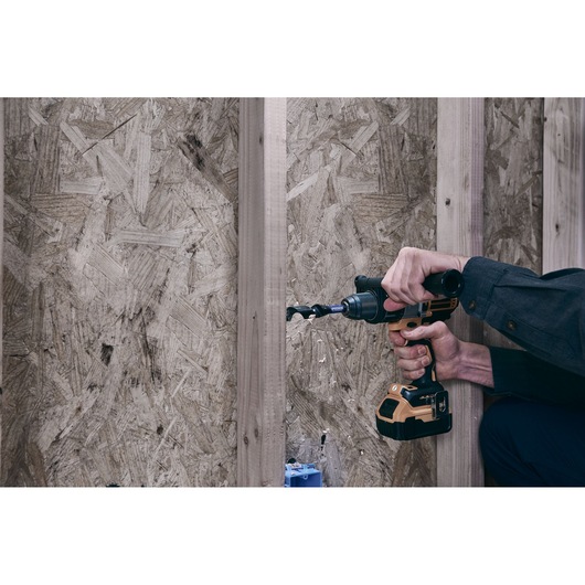 IRWIN drill bit IWAX3017 in use, drilling through wood with a cordless drill in a construction setting.