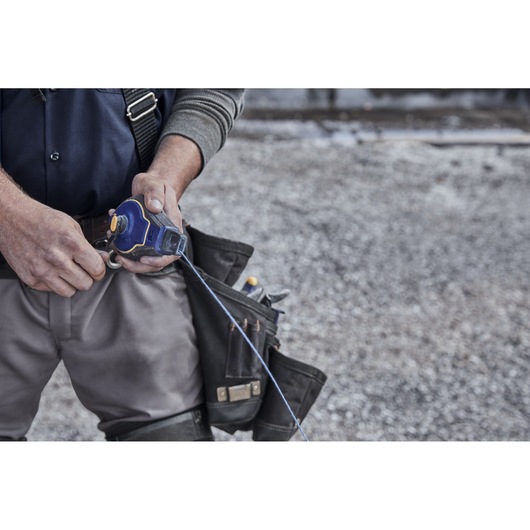 IRWIN IWHT48443 chalk reel with blue casing and line held by worker wearing tool belt at jobsite.