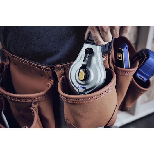 Photo of IRWIN chalk reel IWHT48445 held in leather tool belt pouch next to other hand tools.